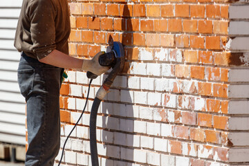 Person grinds brick wall with handheld power tool © schankz