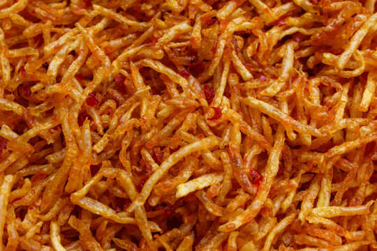 Spicy seasoned fried potato stick snack texture background