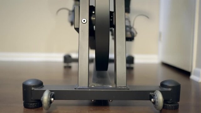 Unrecognizable athlete exercising on spin bike in domestic setting