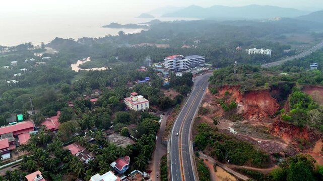 Drone shot capturing the tropical landscape near Palolem Beach, with lush coconut groves, resort buildings, and a long highway stretching through layered greenery. Goa-Karnataka costal highway