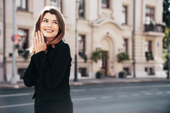 Portrait of young beautiful brunette woman wearing nice trendy suit black jacket clothes. Sexy smiling model posing in the street at sunny day. Fashionable female outdoors. Cheerful and happy