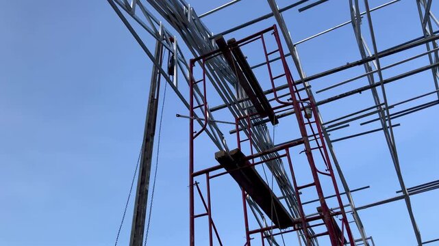 Construction site with metal scaffolding and steel frame structure against a clear blue sky