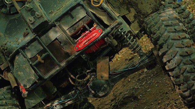 Rugged close up of muddy all terrain vehicle undercarriage. Focus on suspension, axle, and bright red winch highlights power for extreme sports competition. Tilted angle adds dynamic action feel