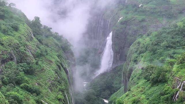 Aerial shot of waterfall in misty green mountains in Maharashtra India