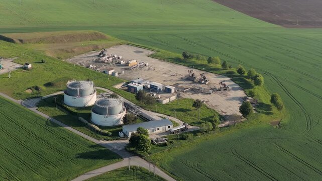 Aerial view of UGS Damborice gas storage facility with large tanks and pump jacks surrounded by green fields in Damborice, South Moravian Region, Czechia.