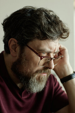 Vertical shot of Caucasian author wearing glasses and  looking at laptop screen while reviewing novel chapter 