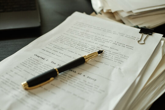 Close up of manuscript pages holding pen and clip, showing editing and proofreading process for fiction writing. Useful for publishing, content creation, copywriting, education
