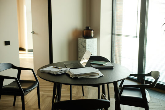 Round office table displaying laptop, paperwork, notebook, pen, suggesting copywriting, planning
