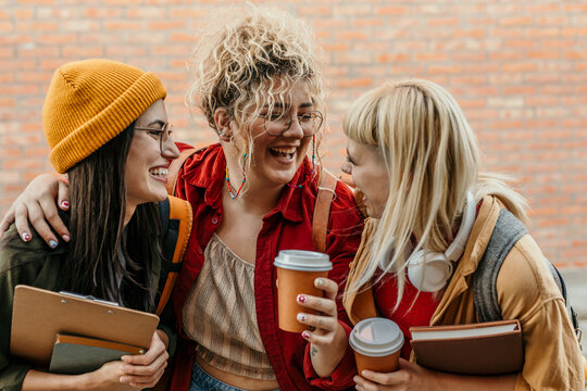 Diverse students laughing together on campus with coffee