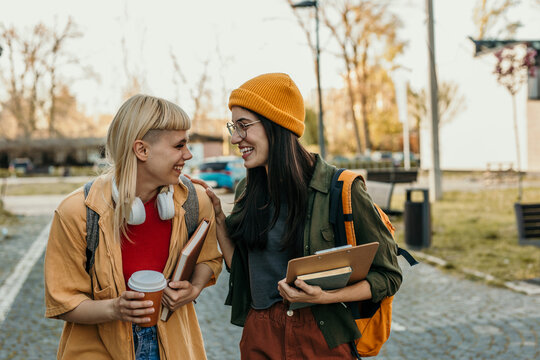 Smiling diverse students walking and talking on campus