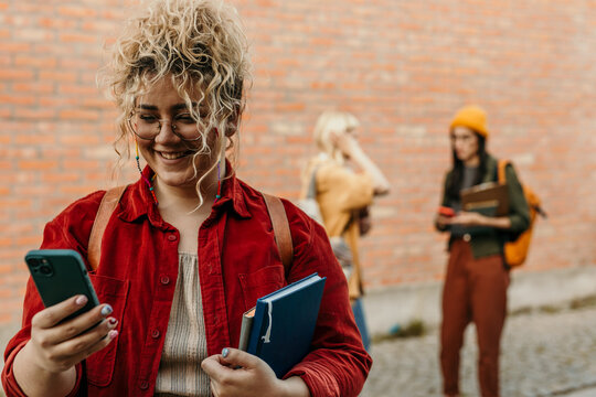 Student smiling and using smartphone on campus