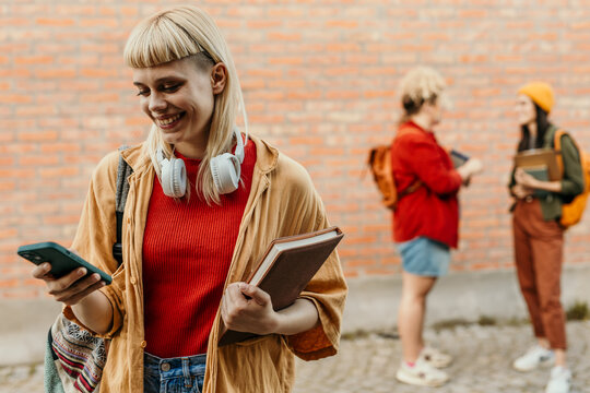 Student smiling while using phone on campus