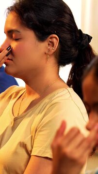 Indian young family doing meditation pranayama at home practicing breathing exercise together indoors during peaceful morning hours in a modern lavish living room promoting yoga health wellness