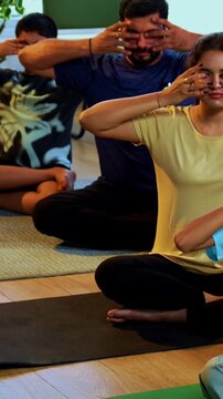 Indian family of four bhramari pranayama or bee breathing exercise practicing yogic breath together indoors during calm morning hours inside a modern home promoting health wellness in yogic style