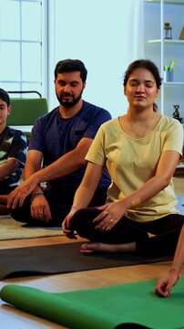 Indian family doing yog asana at home practicing Parsva Sukhasana seated side bend yoga together indoors during calm morning hours inside a modern lavish living space promoting flexibility posture