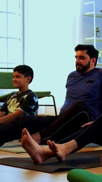 Indian family doing yog asana at home practicing ardha matsyendrasana seated spinal twist yoga together indoors during calm morning hours inside a modern lavish living space promoting health