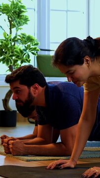 Indian family doing plank exercise at home practicing core strength together with lighthearted mood indoors on floor during family fitness session in a modern lavish living space promoting health
