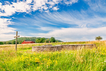 Fototapeta premium Old church ruin with wooden cross in rural landscape