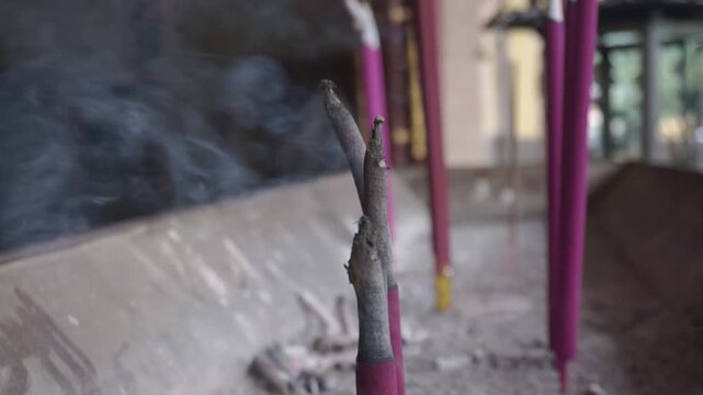 Close-up of smoking incense sticks in a traditional censer with blurred background
