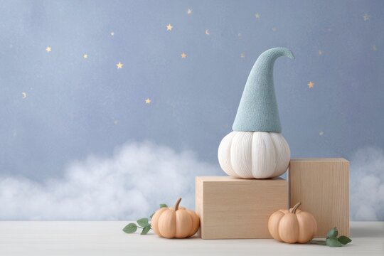 pumpkin with an elf hat, sitting on wooden boxes and surrounded by pumpkins and stars in the night sky.