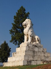 Obraz premium Majestic white stone lion sculpture seated regally atop a tiered monument against a clear blue sky