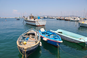 Obraz premium Traditional wooden boats floating in clear turquoise water in the harbor of Procida island, Italy
