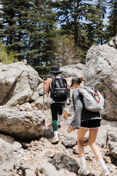 Two women hiking on rocky trail surrounded by trees