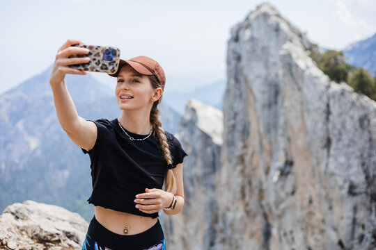 woman taking selfie on mountain hike with rocky cliffs in background