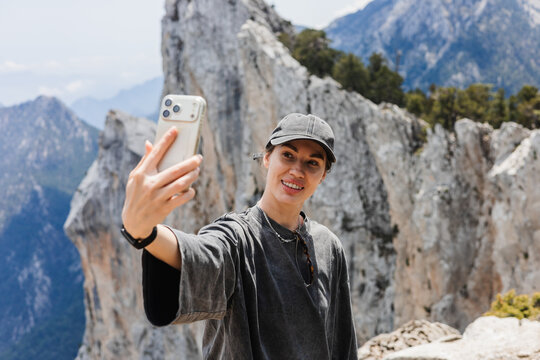 Young woman takes selfie while hiking in mountainous area. Rocky