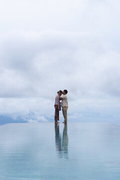 Romantic Balinese couple kissing at infinity pool, Bali, Indonesia