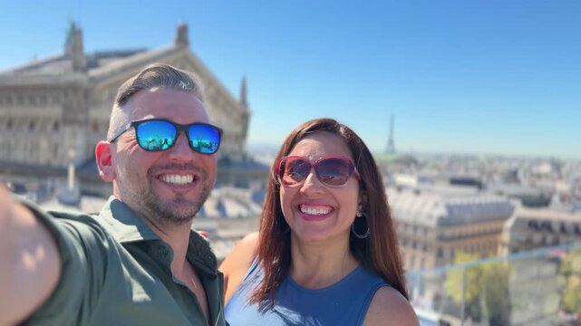 Young couple in love taking a selfie from a rooftop in Paris, with the beautiful skyline and the Eiffel Tower in the background, enjoying their vacation in the french capital