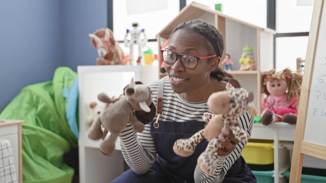 Woman teacher holds giraffe and elephant puppets and gestures with a hand puppet in preschool classroom, wearing glasses and striped shirt; playful learning.