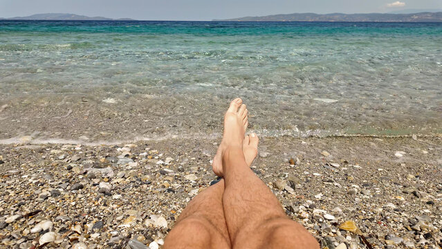 Man sunbathing on a rocky sea ocean beach.