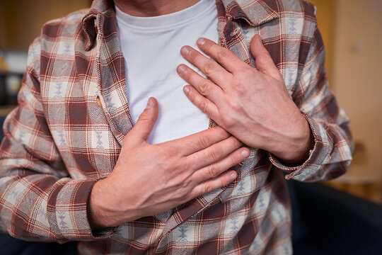 Man with heart problems, chest and abdominal pain at home measuring and checking pulse.