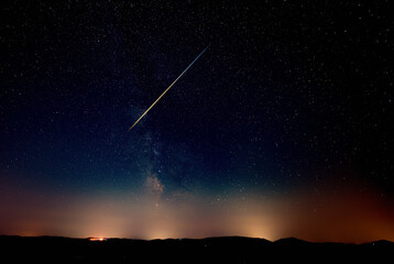 Fototapeta premium Constellation and Milky Way stars on a dark countryside skies with landscape silhouettes.