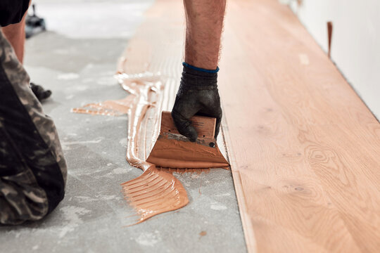 Professional handyman installing laminate flooring in a new apartment.