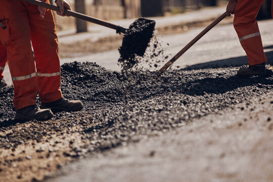 Construction worker working on a new asphalt layer on a public street.
