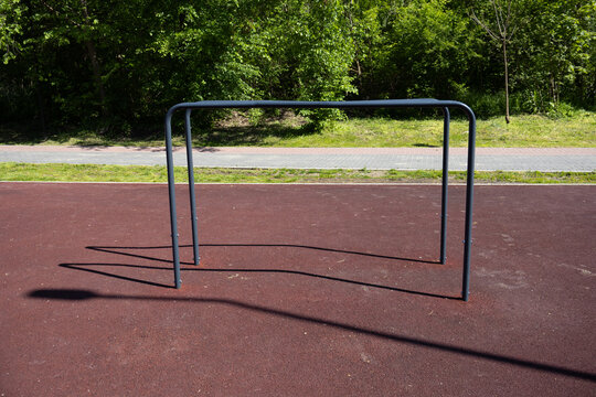 Front view of metal dipping bars in a public fitness area, designed for bodyweight strength training on a shock-absorbing surface