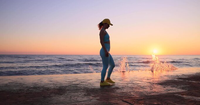 Fit woman showing muscles at the beach during summer vacation. Slow motion
