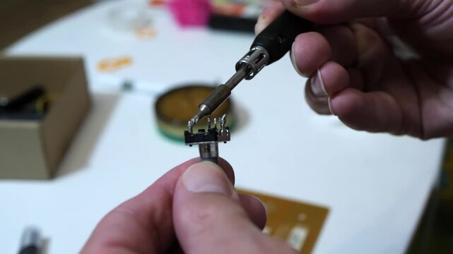 Hands soldering small electronic component with soldering iron close-up