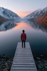 Fototapeta premium Solitary person on wooden dock at mountain lake sunrise reflection for calm landscape background and travel banner