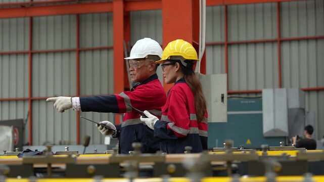 A team of engineers and staff are inspecting the production line system at a metal sheet and roofing factory. (4K video)