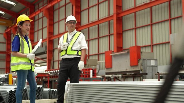 A team of engineers and staff are inspecting the production line system at a metal sheet and roofing factory. (4K video)