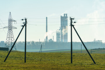 Fototapeta premium A large petrochemical enterprise on the background of a wheat field. Next to the agricultural field there's a factory for the production of chemical fertilizers. smoke escapes from factory chimneys