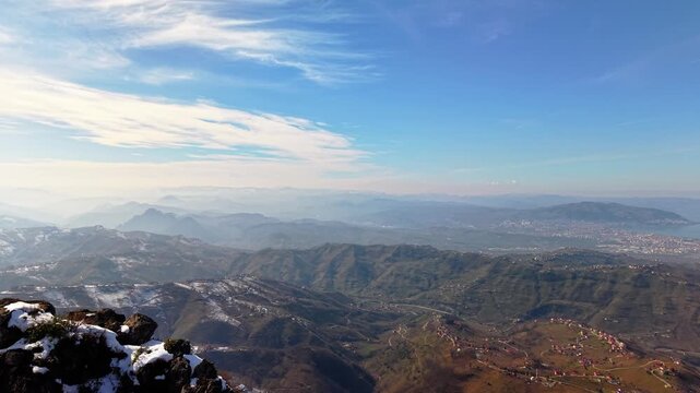 A professional 4K drone shot featuring a precise fly-through between two towering, snow-covered mountain peaks. The camera passes through a narrow 15-meter gap, revealing a breathtaking vista of a vas