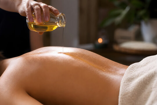 Warm massage oil drizzled onto bare back