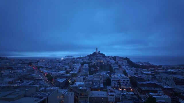 Stunning transition from blue hour to deep night over San Francisco's North Beach neighborhood, with Coit Tower on Telegraph hill and traffic creating light trails on the streets below