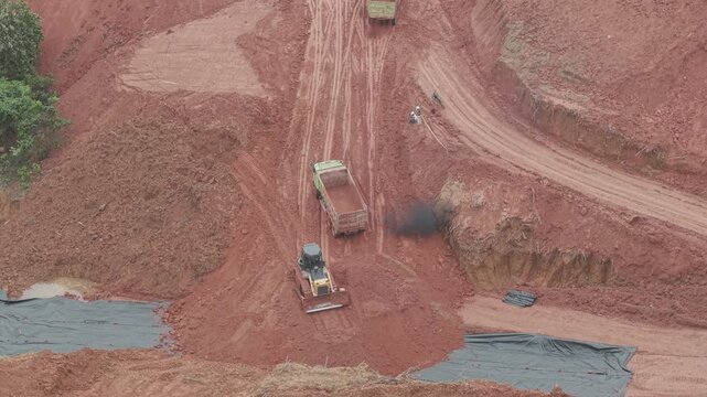 A crawler bulldozer is leveling the fill soil unloaded from a truck for road construction