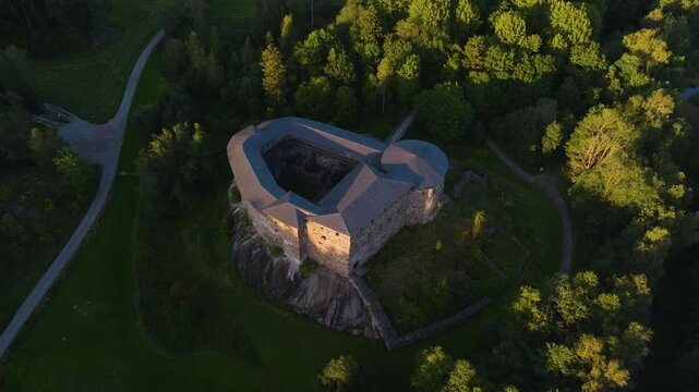 Drone rising backwards from the Raasepori castle ruins, summer sunset in Finland