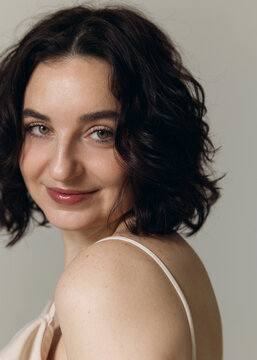 A studio portrait of a beautiful girl with curly hair and a lovely smile 